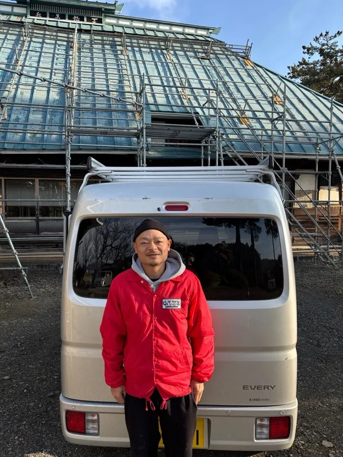 瀧澤屋根工業 代表。足場を組んだ現場の前