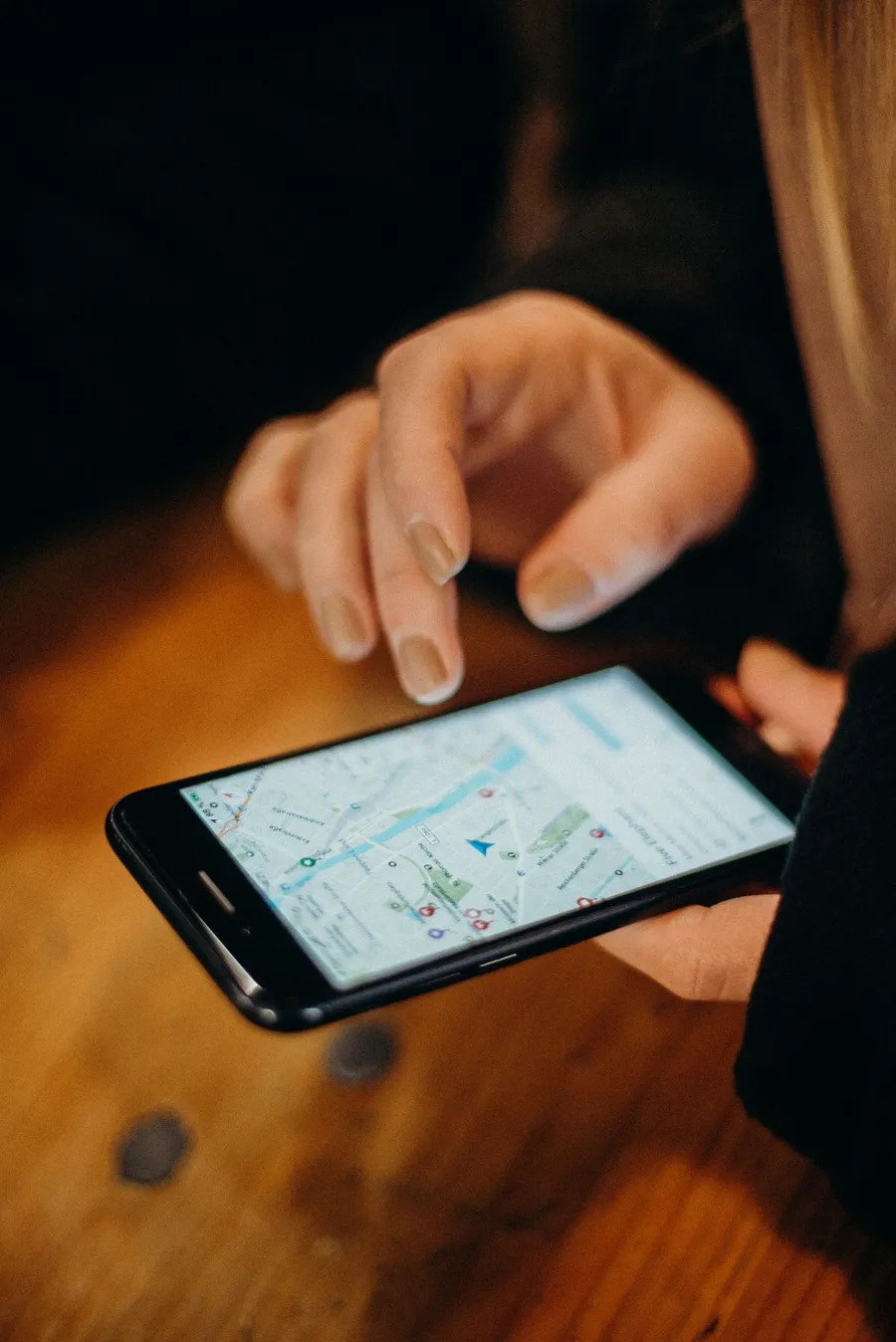 スマホの地図アプリを指で操作している手元。画面には街の地図が表示されている。